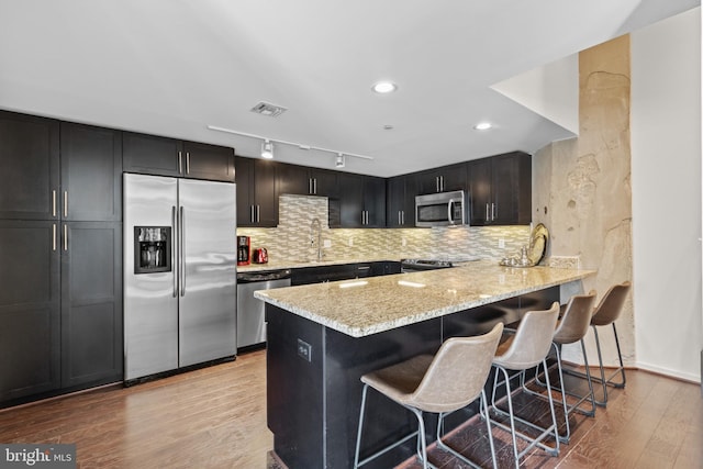 kitchen with tasteful backsplash, appliances with stainless steel finishes, a breakfast bar area, and kitchen peninsula