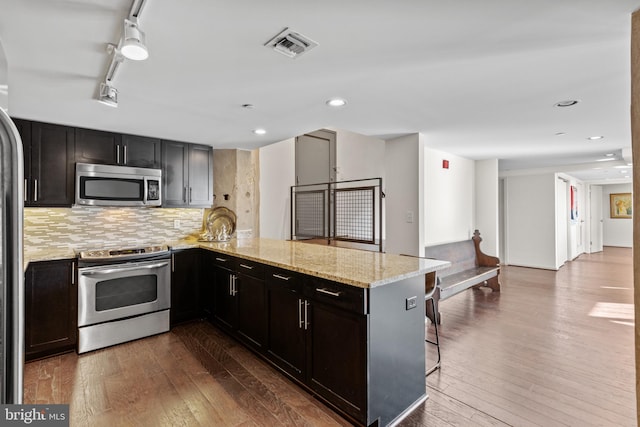 kitchen featuring stainless steel appliances, hardwood / wood-style flooring, a kitchen breakfast bar, and kitchen peninsula