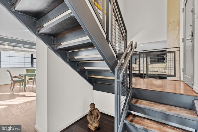 stairway with a towering ceiling and wood-type flooring