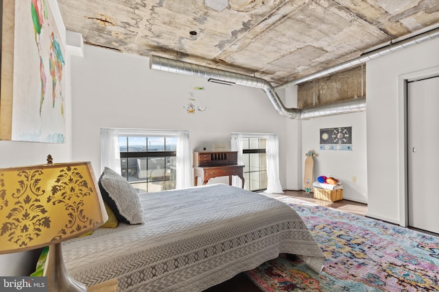 bedroom featuring hardwood / wood-style flooring and a towering ceiling