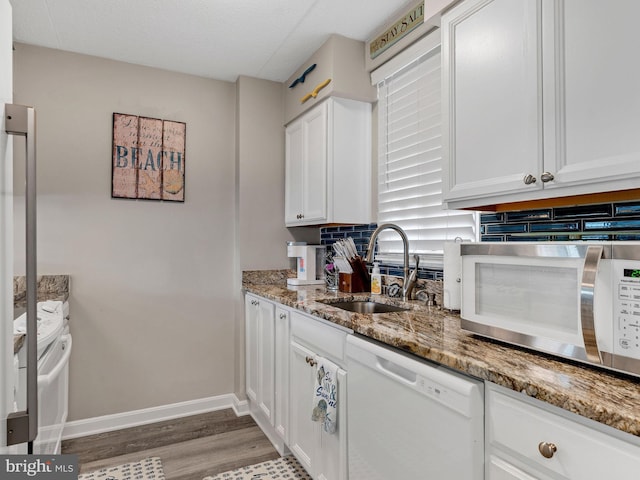 kitchen featuring dishwasher, light stone counters, light wood-type flooring, white cabinetry, and a sink