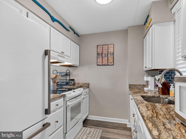 kitchen with white appliances, stone countertops, under cabinet range hood, white cabinetry, and a sink