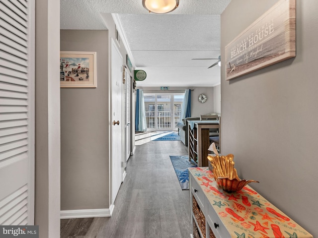 hall with a textured ceiling, baseboards, and dark wood-style flooring