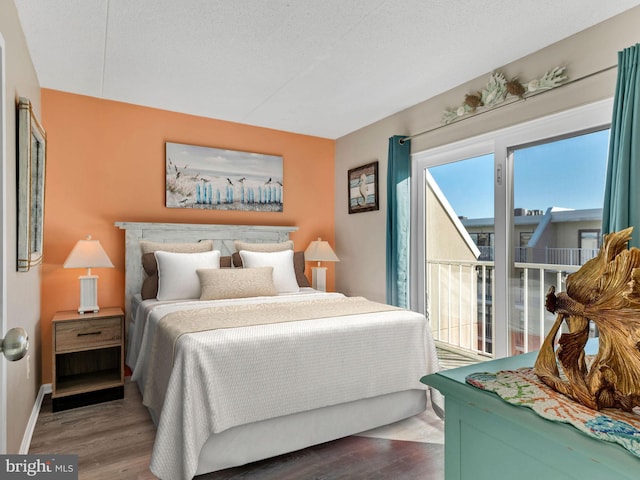 bedroom featuring access to outside, a textured ceiling, baseboards, and wood finished floors