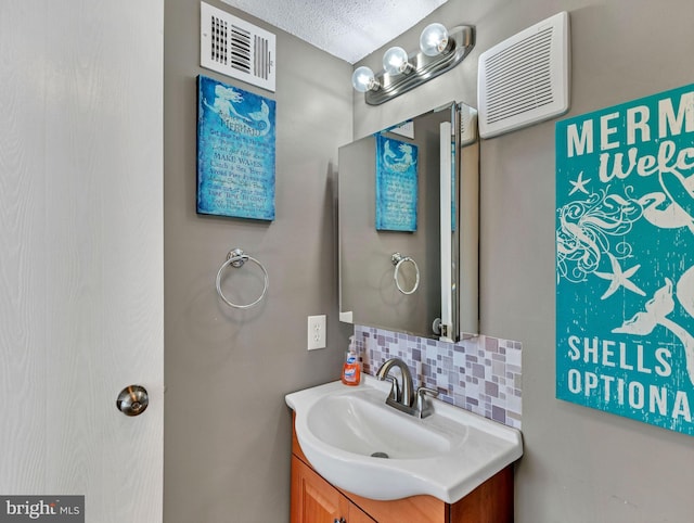 bathroom featuring a textured ceiling, tasteful backsplash, vanity, and visible vents