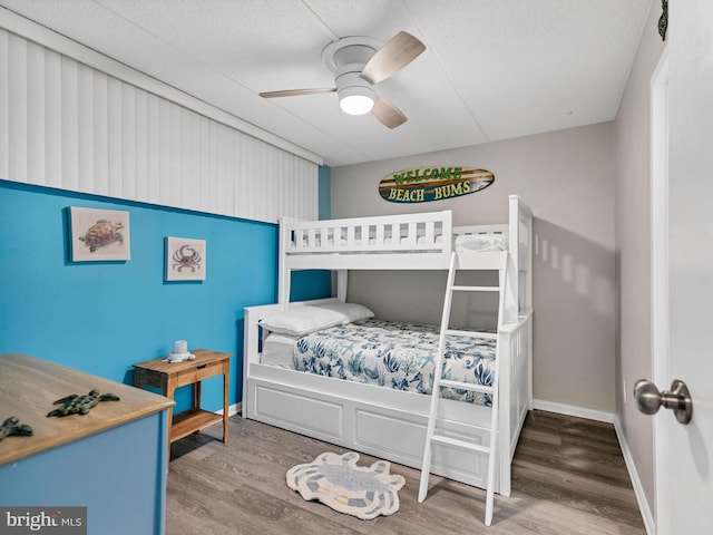 bedroom with ceiling fan, baseboards, and wood finished floors