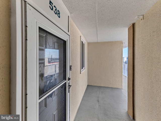 hallway with a textured wall and a textured ceiling