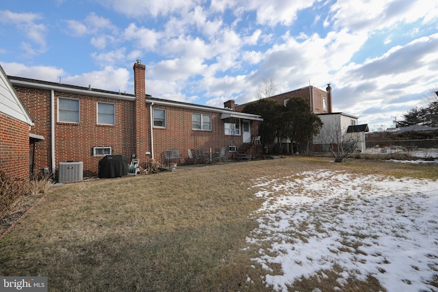 snow covered rear of property with a yard and central air condition unit