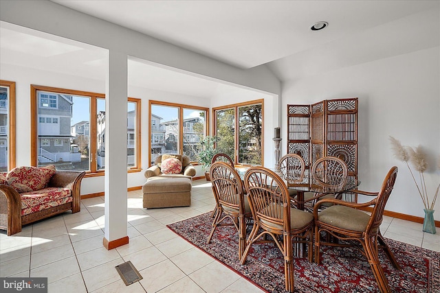 dining room with light tile patterned floors, baseboards, and vaulted ceiling