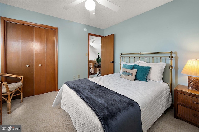 carpeted bedroom featuring ceiling fan, a textured ceiling, and a closet