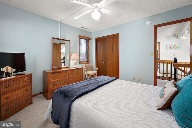 bedroom with visible vents, light colored carpet, ceiling fan, a textured ceiling, and a closet