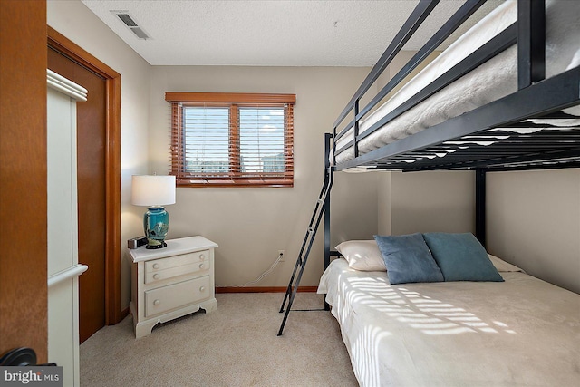 bedroom with light colored carpet, visible vents, a textured ceiling, and baseboards