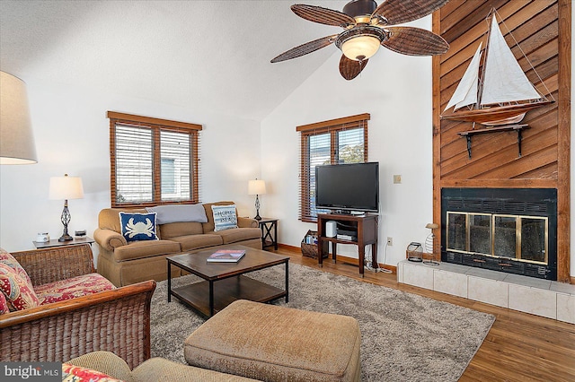 living room with lofted ceiling, a healthy amount of sunlight, a tile fireplace, and wood finished floors