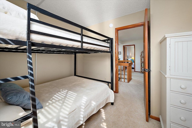 bedroom featuring light colored carpet, a textured ceiling, and baseboards