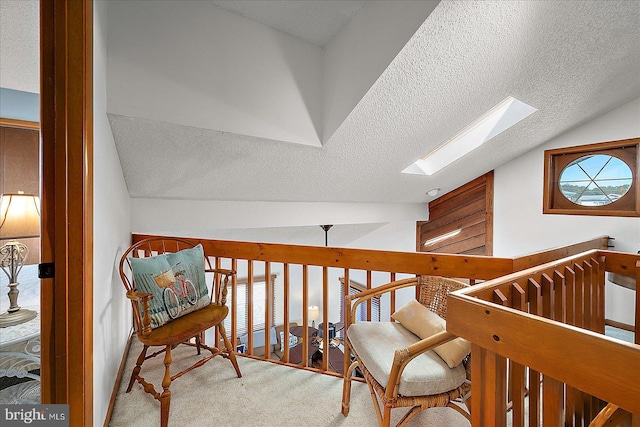 hallway featuring a textured ceiling, vaulted ceiling with skylight, and carpet flooring