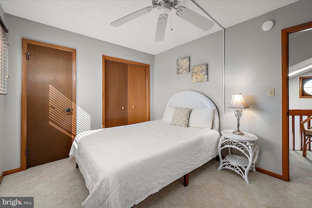 bedroom with a textured ceiling, carpet floors, a closet, and baseboards