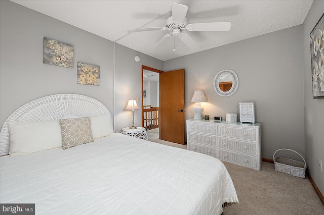 carpeted bedroom with a textured ceiling, a ceiling fan, and baseboards