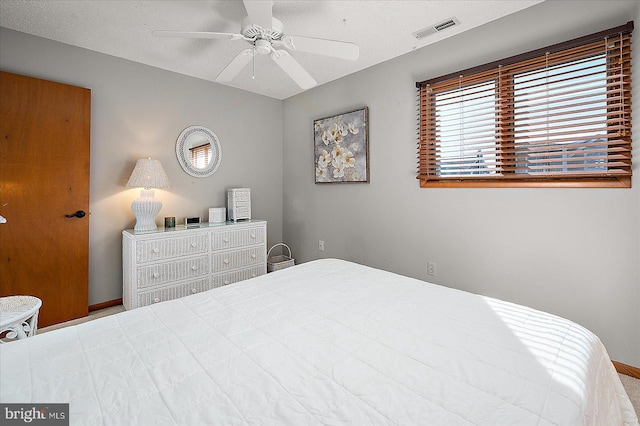 bedroom with baseboards, a textured ceiling, visible vents, and a ceiling fan