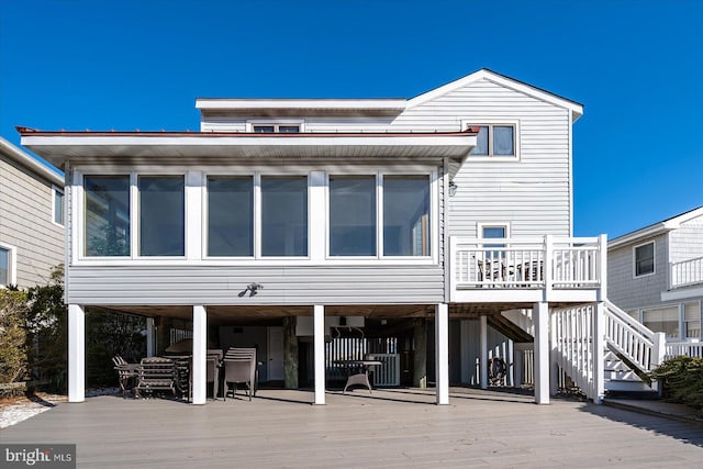 rear view of property with a carport, stairway, and a deck