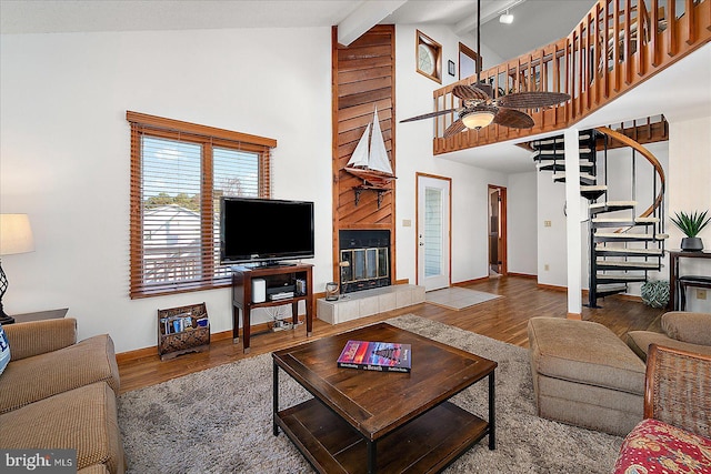 living room with a tile fireplace, wood finished floors, baseboards, stairway, and beamed ceiling