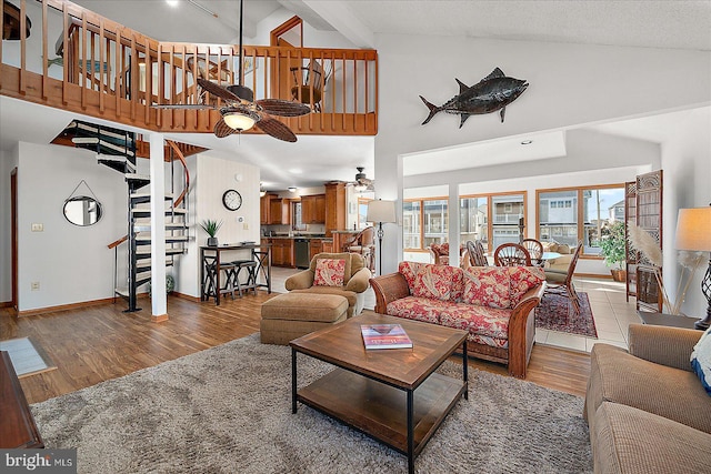 living room featuring high vaulted ceiling, wood finished floors, a ceiling fan, baseboards, and stairway