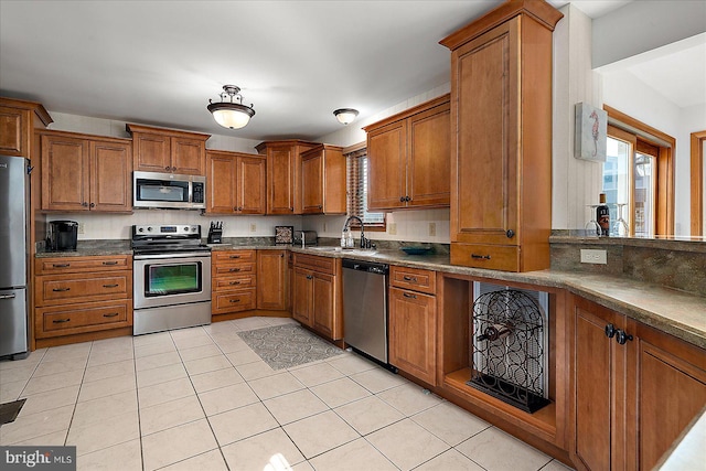 kitchen with a wealth of natural light, appliances with stainless steel finishes, brown cabinets, and a sink