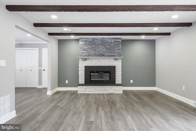 unfurnished living room featuring hardwood / wood-style flooring, a fireplace, and beamed ceiling