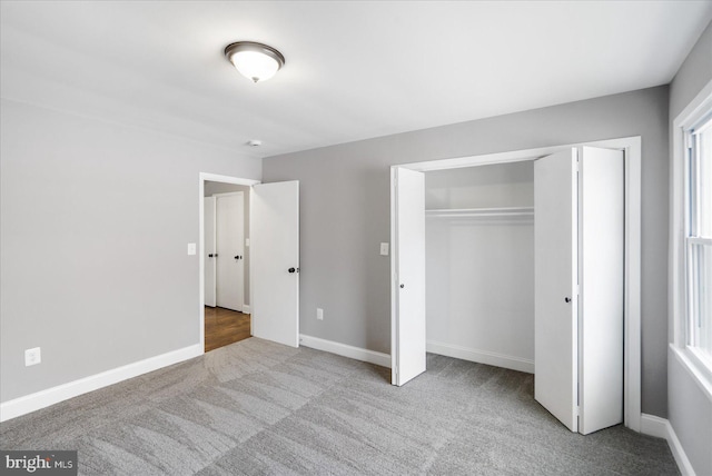 unfurnished bedroom featuring light carpet, multiple windows, and a closet