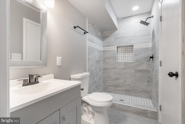 bathroom featuring vanity, toilet, and a tile shower