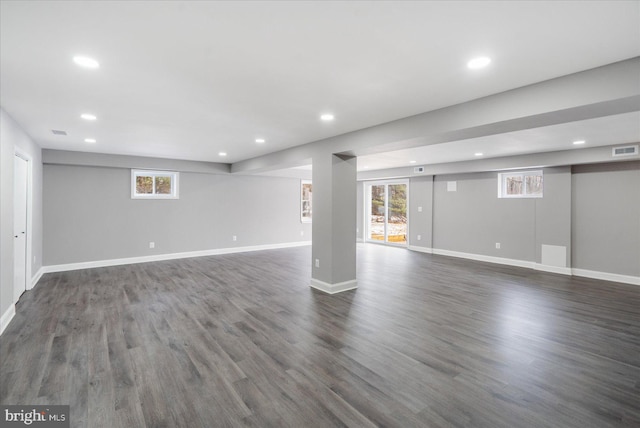 basement featuring plenty of natural light and dark hardwood / wood-style flooring