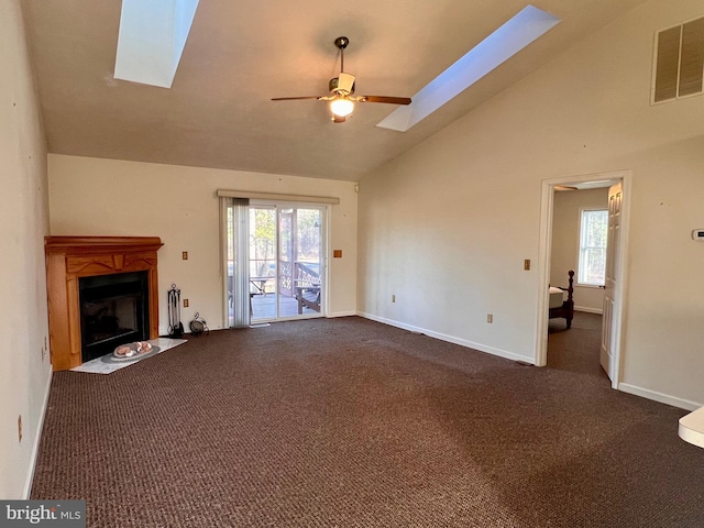 unfurnished living room with a wealth of natural light, a skylight, visible vents, and dark carpet