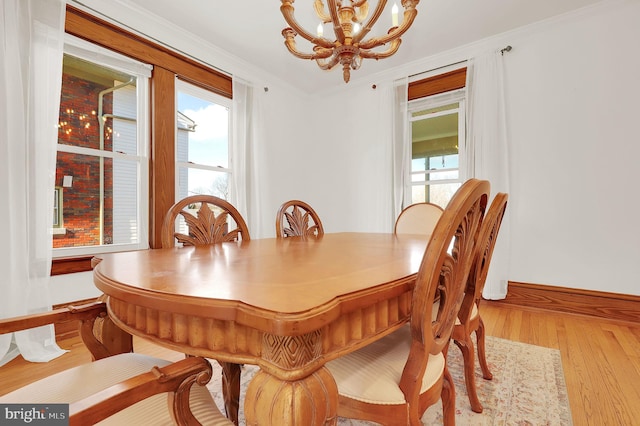 dining area with light wood-type flooring, crown molding, and a notable chandelier