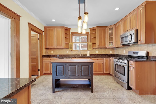 kitchen with dark stone countertops, sink, pendant lighting, crown molding, and stainless steel appliances