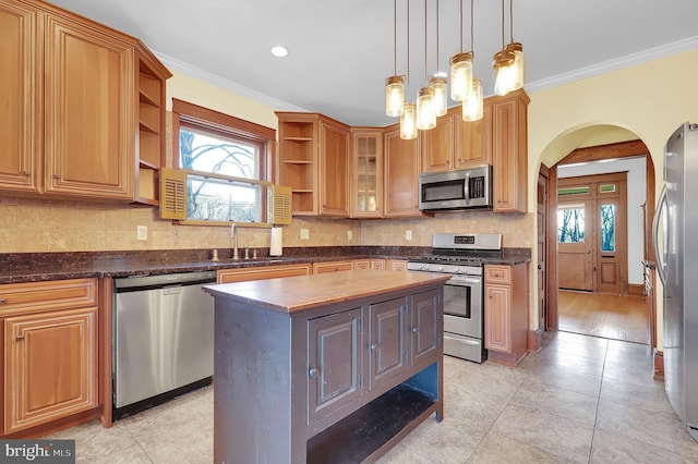 kitchen with a kitchen island, sink, a healthy amount of sunlight, appliances with stainless steel finishes, and crown molding