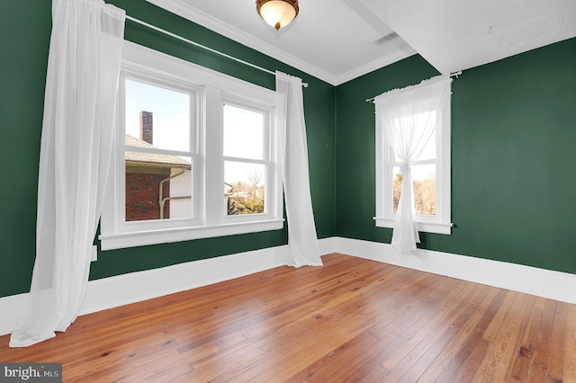 spare room with hardwood / wood-style floors and crown molding