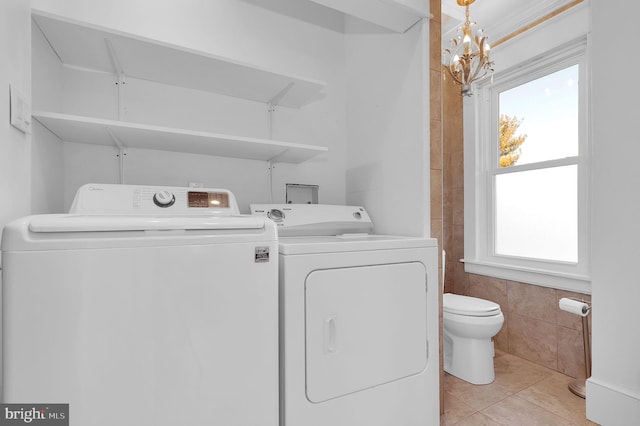 laundry room with a notable chandelier, light tile patterned floors, washer and clothes dryer, and a wealth of natural light