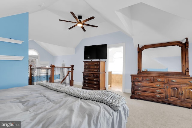 bedroom featuring multiple windows, lofted ceiling, light colored carpet, and ensuite bath