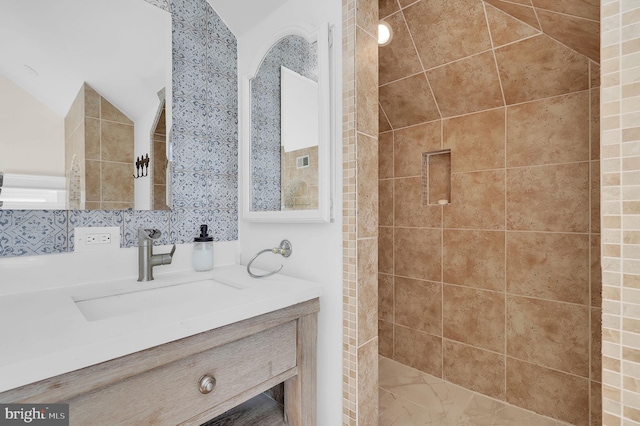 bathroom featuring vanity, vaulted ceiling, and a tile shower