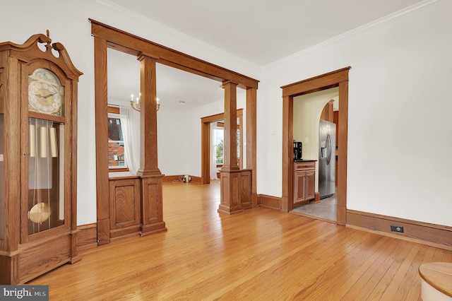 empty room featuring light wood-type flooring, decorative columns, and ornamental molding