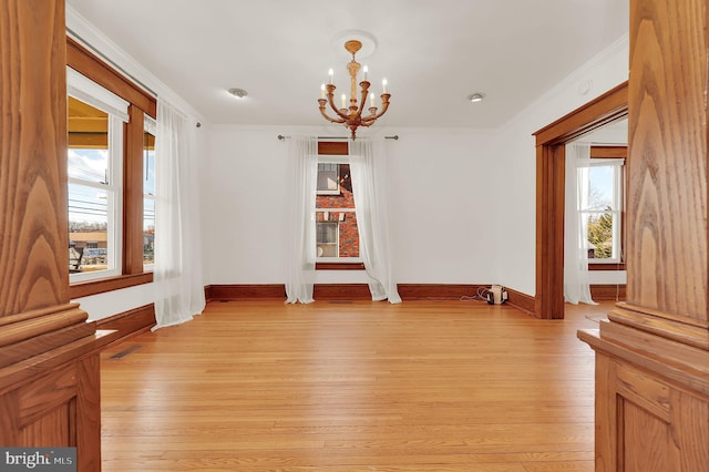 unfurnished room with ornamental molding, light hardwood / wood-style floors, and a chandelier