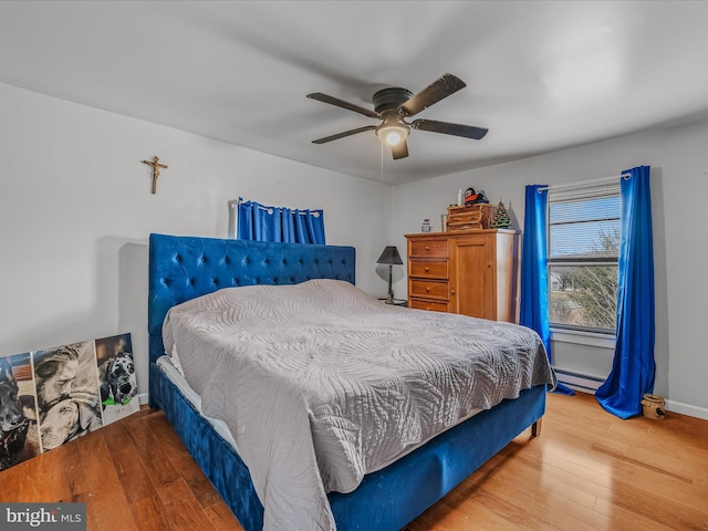 bedroom with wood-type flooring, ceiling fan, and a baseboard radiator