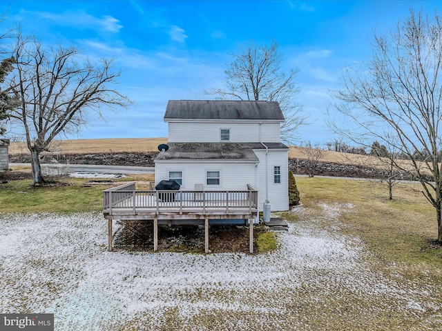 snow covered back of property with a wooden deck