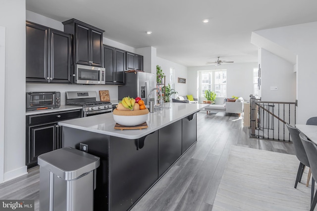 kitchen with a kitchen island with sink, a breakfast bar area, stainless steel appliances, and light wood-type flooring