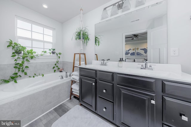 bathroom featuring hardwood / wood-style flooring, vanity, and a relaxing tiled tub