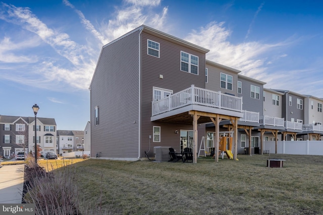 back of property with a yard, central AC, and a playground