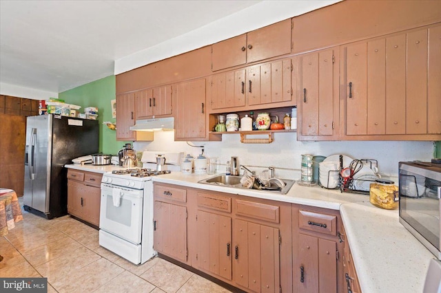 kitchen with sink, light tile patterned floors, stainless steel fridge, and white range with gas stovetop
