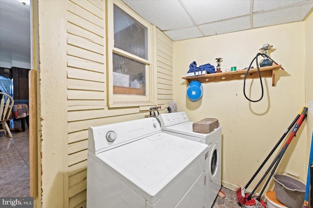 laundry area featuring wooden walls and separate washer and dryer