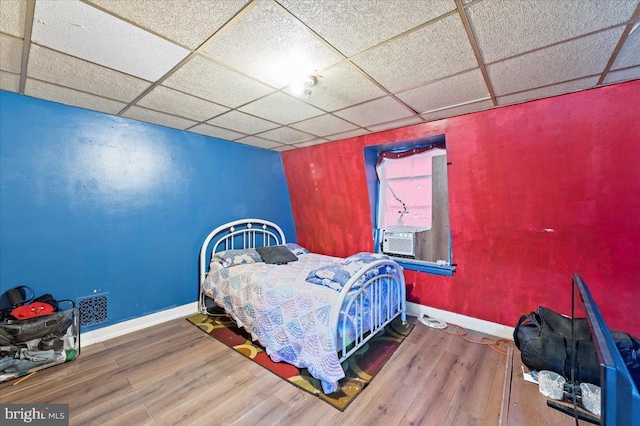 bedroom featuring hardwood / wood-style floors, a paneled ceiling, and cooling unit