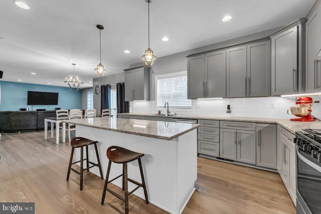 kitchen featuring a breakfast bar, sink, gray cabinets, a kitchen island, and pendant lighting