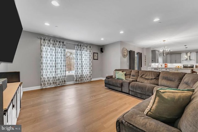 living room featuring a notable chandelier, light hardwood / wood-style floors, and sink